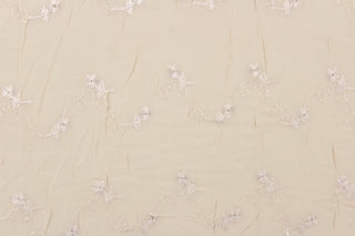 This chiffon fabric features a floral eyelet design in cream against a pale khaki.