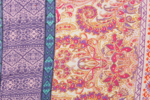 This chiffon fabric features a paisley design in orange, purple, pink, white, turquoise, and gray. 