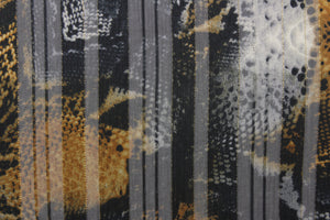 This chiffon fabric features a snakeskin design in tan, black, gray, and gold.
