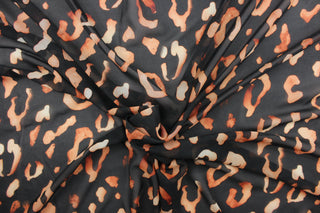 This chiffon fabric features a leopard design in a faded out orange against black. 