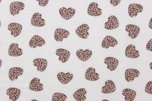 This chiffon fabric features a heart design with a leopard design in taupe and red against a white background. 