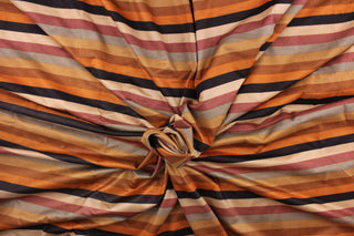 This suede lycra fabric features a stripe design in orange, nude, brown, tan, beige, dusty rose, and taupe . 
