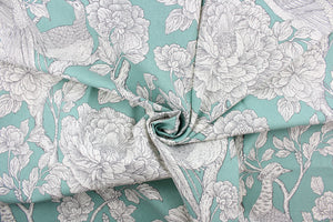 This fabric features a bird and floral design in  white and gray against an aqua background. 