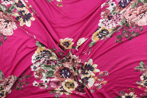 This jersey fabric features a floral design in pink, mauve, purple, green, golden tan, deep pink and white. 
