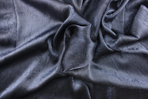 This taffeta fabric features a crinkle in iridescent in a dark gray blue . 