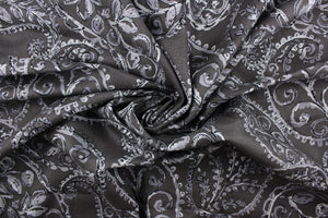 This fabric features a leaf design in gray and black against a dark gray background .