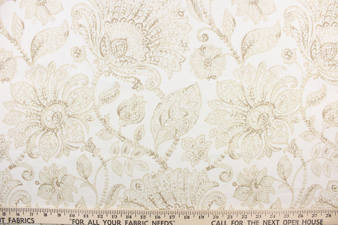 This linen fabric features a floral design in beige or khaki and white. 