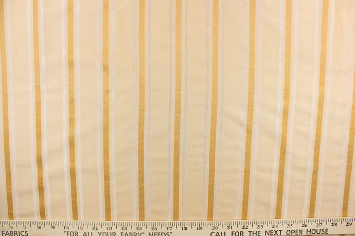 This stunning yarn dyed fabric features a striped pattern in light beige, with gold and champagne stripes . 