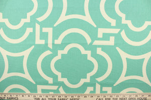 This fabric features a geometric design in white against turquoise green. 