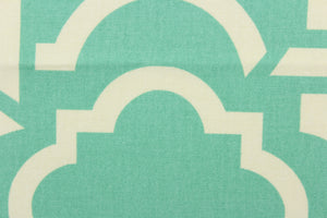 This fabric features a geometric design in white against turquoise green. 