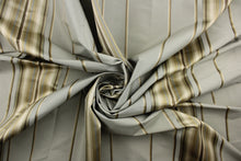 Load image into Gallery viewer, This stunning yarn dyed fabric features a multi width striped pattern in gray, brown, gold, and shades of khaki. Enhancing the various colors of the stripes is a slight sheen.
