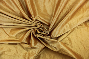 This taffeta fabric features a crinkle in iridescent gold. 