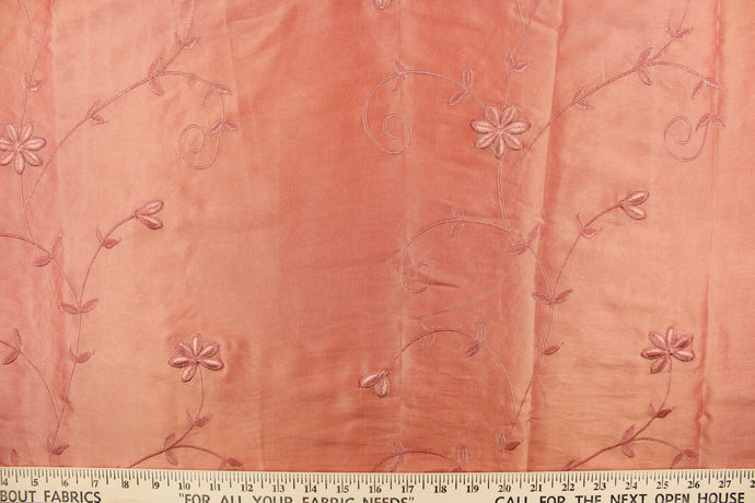  This beautiful fabric features an embroider floral design in a iridescent peachy pink with gold tones. 