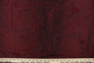 This beautiful fabric features an embroider floral design in a iridescent red wine color