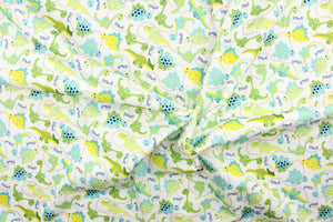 This cute playful print features dinosaurs in green, blue, yellow and brown on a white background.