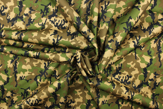 This fabric features a camo pattern in green, black, brown and beige.