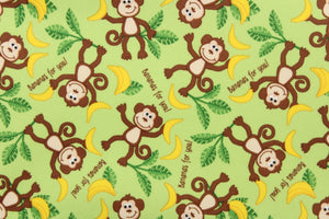  This cute playful print features monkeys with bananas on a light green background.