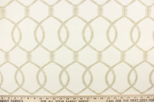  This fabric features a lattice design with overlapping oval shapes in light brown on an ivory background. 