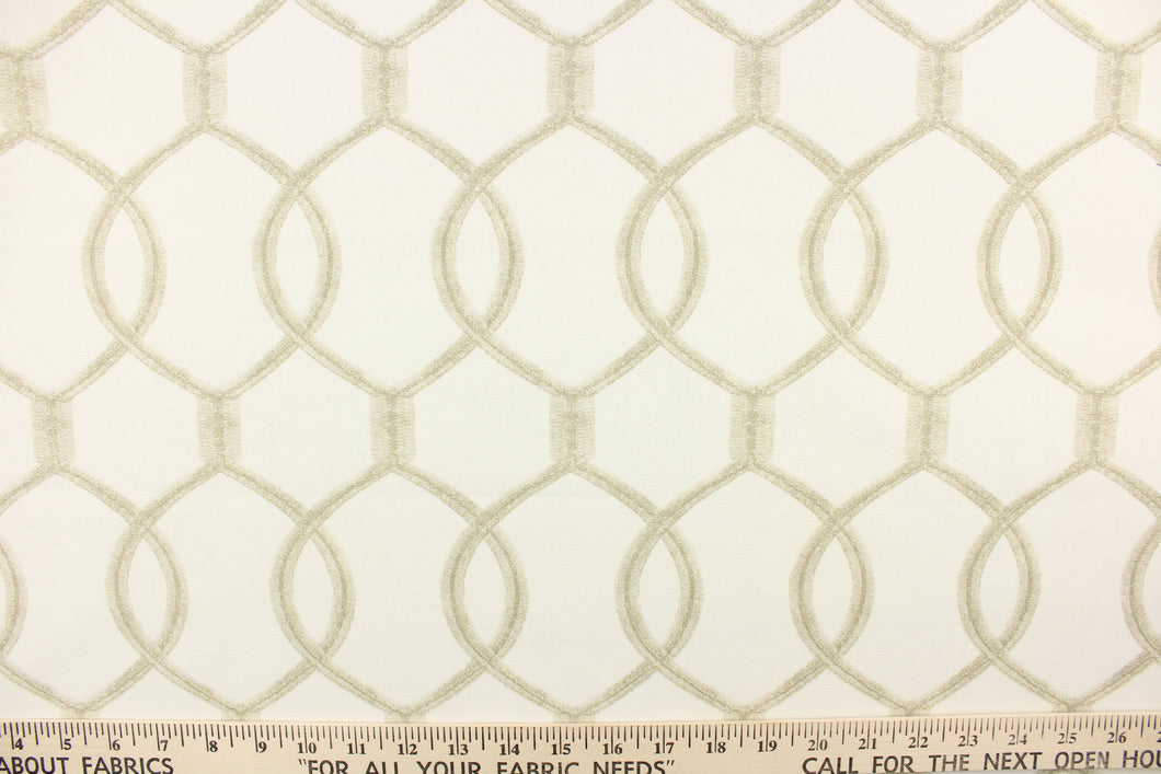  This fabric features a lattice design with overlapping oval shapes in light brown on an ivory background. 