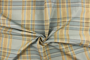 This fabric features a plaid design in blue gray, beige, tan, dark brown and light gold.