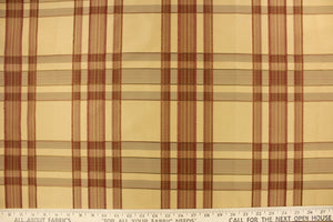 This fabric features a plaid design in tan, red and brown.