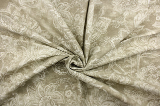 This fabric features a whimsical floral design in a off white against a grayish beige .