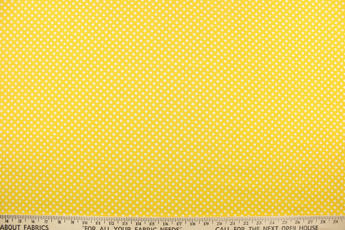 This quilting print features a polka dot design in white against a bright yellow 