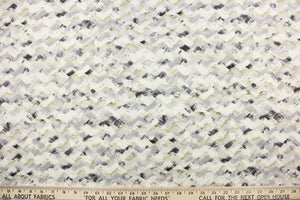This fabric features a chevron design in light gray, black, white and a golden beige.