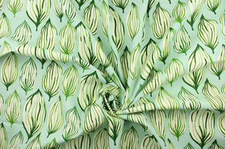 This fabric features a tropical leaf design in green and dull white against a light blue background. 