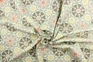 This fabric features a floral medallion design in shades of gray, golden beige, coral, turquoise, and dull white. 
