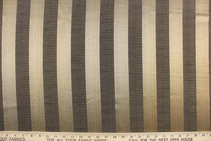  This stunning yarn dyed fabric features a  wide striped pattern in black and gold . Enhancing the various colors of the stripes is a slight sheen.