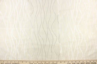 This sheer fabric features wavy line design in white .