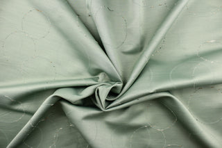 This jacquard fabric features a circle design in moss green with hints of champagne, cream, green, and beige.