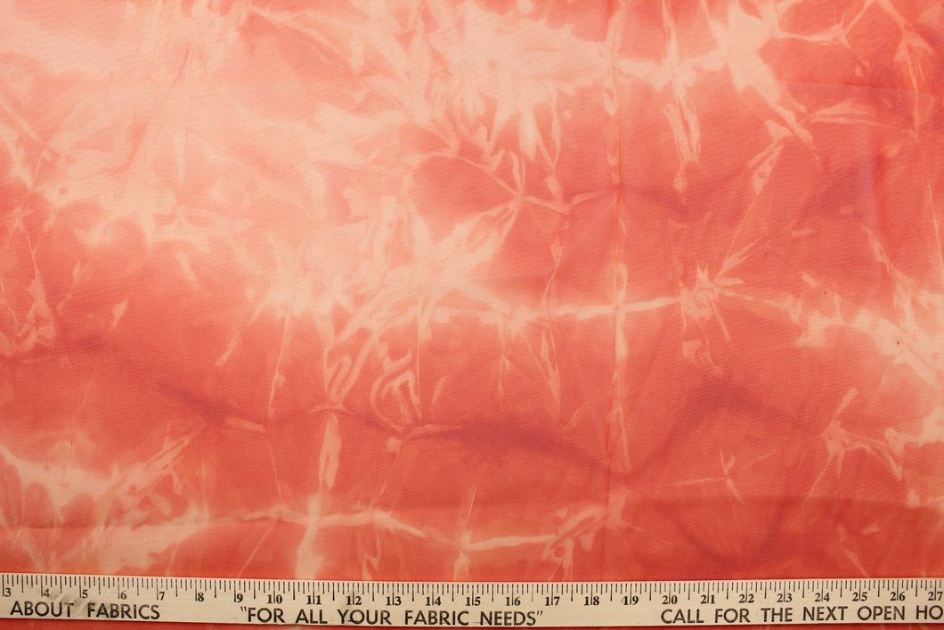This sheer fabric features a tie dye design in orange.