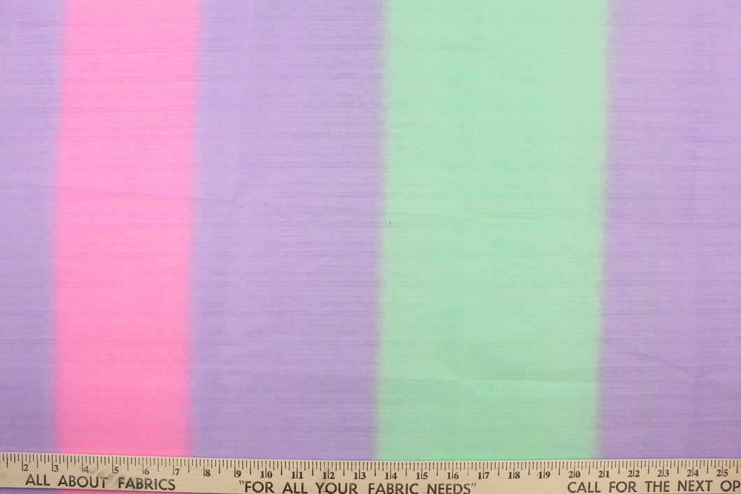A sheer, semi firm, tulle in a purple, green and pink .