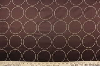 This fabric features large circles in beige with blue tones against a brown background.  It has a soft drapable hand and would be ideal for swags, window scarves and drapery panels.