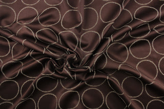 This fabric features large circles in beige with blue tones against a brown background.  It has a soft drapable hand and would be ideal for swags, window scarves and drapery panels.
