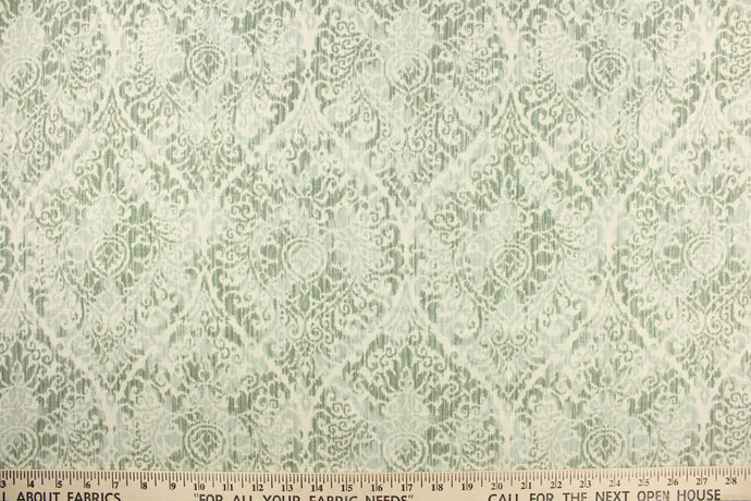 This fabric features a damask pattern in varying shades of green on a off white background.  It has a distressed look enhancing the design.  Uses include drapery, pillows, bedding, light upholstery and home decor.  It has a soft workable hand and is durable with 20,000 double rubs.