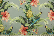 Load image into Gallery viewer, This outdoor fabric features a tropical floral and bird design in shades of coral, beige, green, blue, black, gray, yellow and red set against a taupe background.

