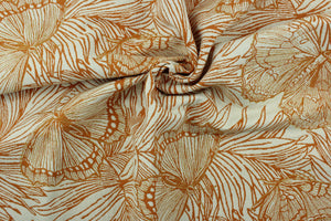 This fabric features a floral and butterfly design in orange with hints of gold set against an off white background .