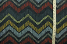 Load image into Gallery viewer, This fabric features a chevron design in pale blue, golden yellow, brick red, taupe, dark gray, and green set against a dull black background . 
