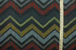 This fabric features a chevron design in pale blue, golden yellow, brick red, taupe, dark gray, and green set against a dull black background . 