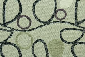 This fabric features a unique design in gray, black, beige, purple, taupe, and cream set against a beige background with a latex backing.