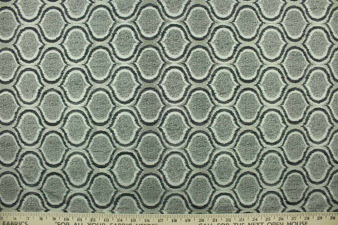This fabric features a geometric design in sliver, gray, black, and white with a latex backing. 