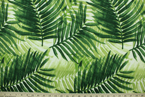 This outdoor fabric features a tropical leaf design in shades of green set against a white background. 