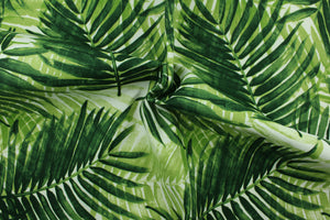 This outdoor fabric features a tropical leaf design in shades of green set against a white background. 