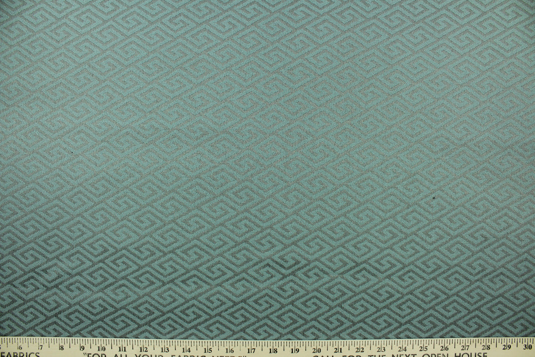 This fabric features a geometric design in gray set against a light turquoise blue with a latex backing. 