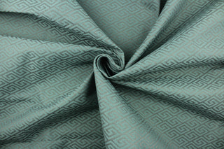 This fabric features a geometric design in gray set against a light turquoise blue with a latex backing. 