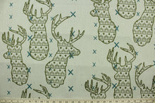 Load image into Gallery viewer, This fabric features a Elk head design in green and turquoise set against a beige background with a latex backing. 
