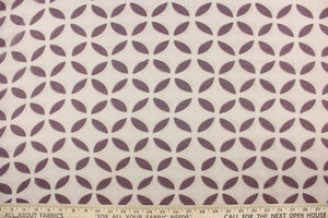  This sheer fabric features a flower design in plum purple against a pale beige 